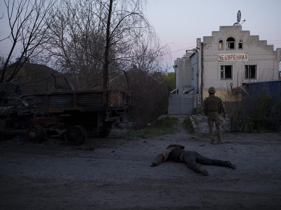 Un militare ucraino si trova accanto al corpo di un sospetto soldato russo, nel villaggio di Vilkhivka, recentemente riconquistato dalle forze ucraine vicino a Kharkiv, Ucraina. (AP Photo/Felipe Dana)