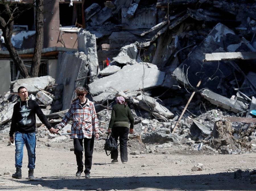 I residenti locali passano davanti a un edificio distrutto durante il conflitto Ucraina-Russia nella città portuale meridionale di Mariupol. REUTERS/Alexander Ermochenko