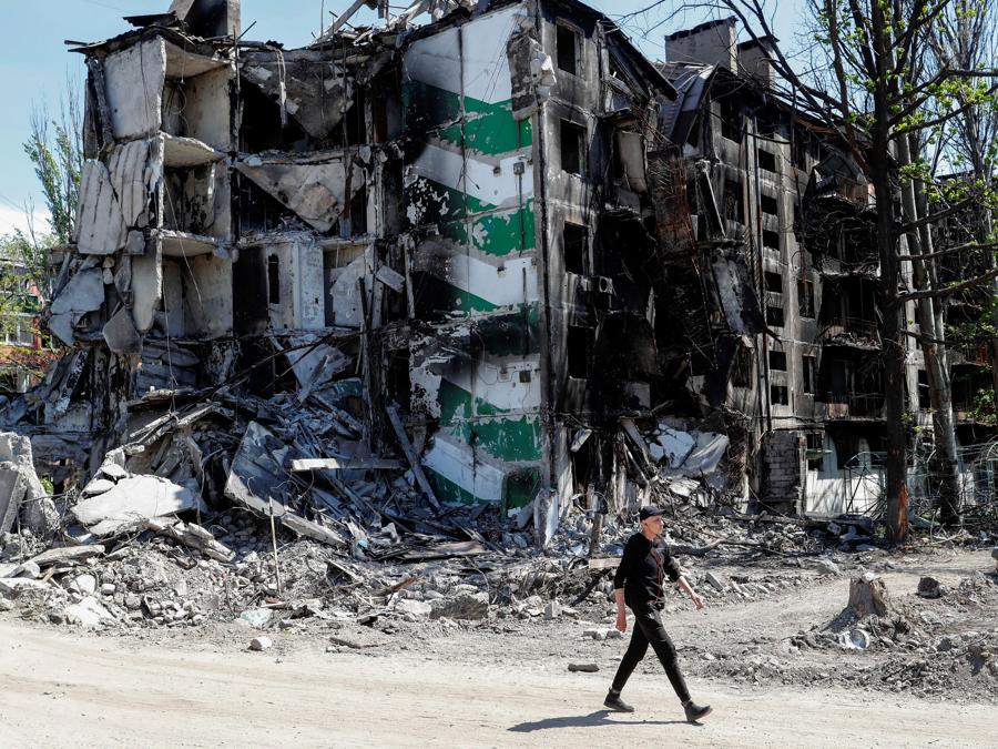 Un uomo cammina davanti a un edificio residenziale distrutto durante il conflitto Ucraina-Russia nella città portuale meridionale di Mariupol. REUTERS/Alexander Ermochenko
