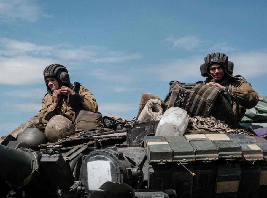 Soldati ucraini siedono su un carro armato trasportato da un trasportatore vicino a Bakhmut, nell’Ucraina orientale. (Photo by Yasuyoshi CHIBA / AFP)