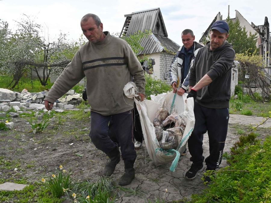 Gli abitanti ucraini trasportano il corpo di uno dei tre civili riesumati da una tomba  nel cortile di una casa nel villaggio di Stepanky, vicino a Kharkiv. (Photo by SERGEY BOBOK / AFP)