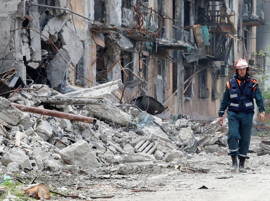 Un membro del Ministero delle Emergenze della Russia cammina vicino a un edificio residenziale distrutto durante il conflitto Ucraina-Russia nella città portuale meridionale di Mariupol. REUTERS/Alexander Ermochenko