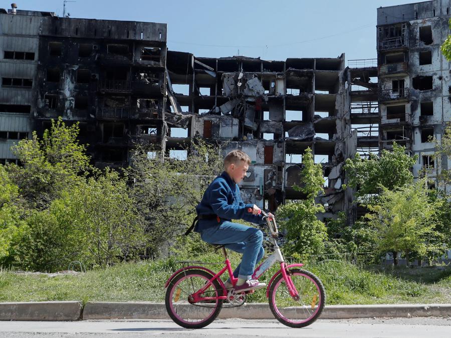 Un ragazzo va in bicicletta vicino a un edificio residenziale distrutto durante il conflitto Ucraina-Russia nella città portuale meridionale di Mariupol. REUTERS/Alexander Ermochenko
