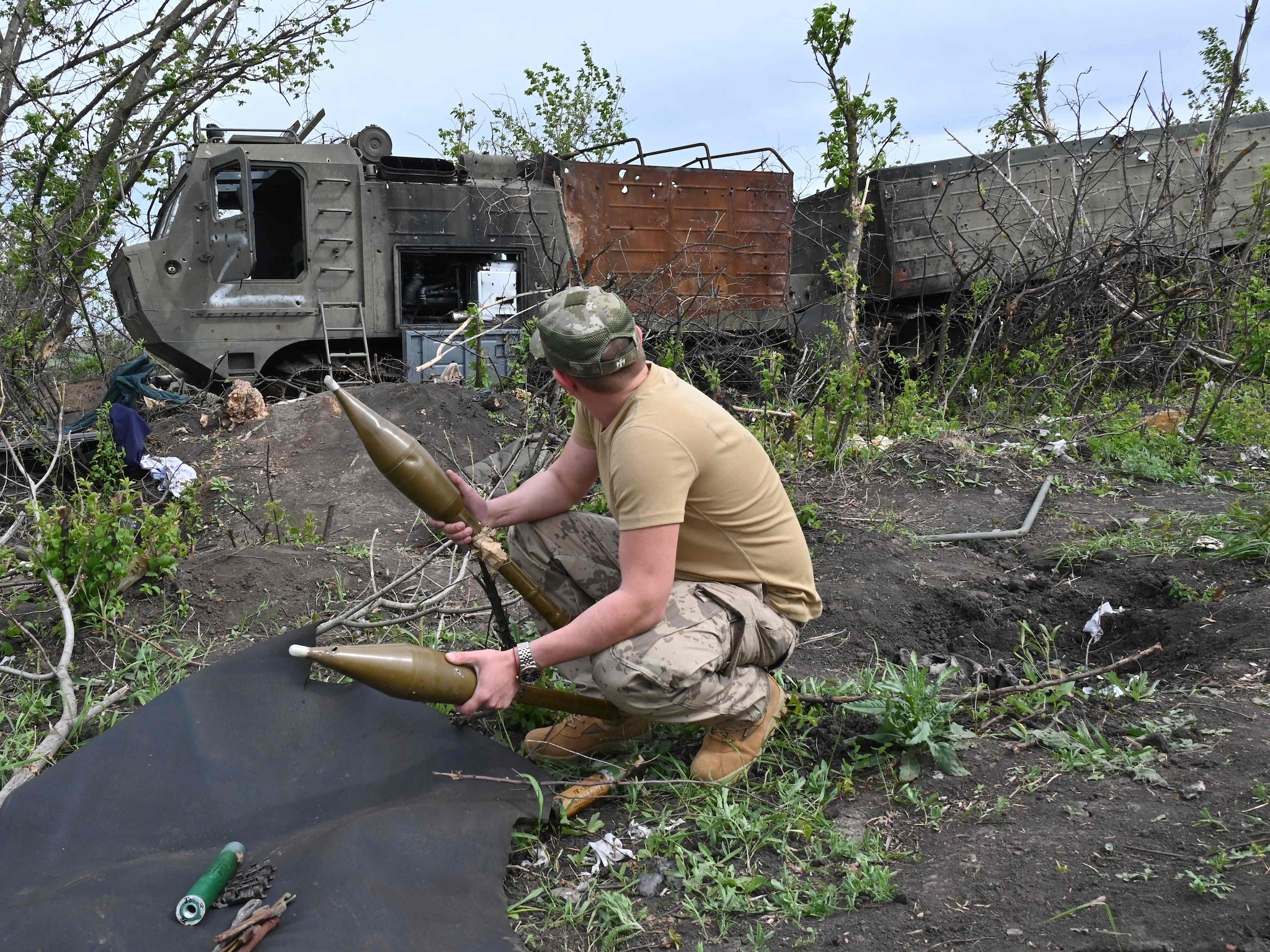 Un militare ucraino ispeziona munizioni abbandonate accanto a un veicolo militare russo distrutto vicino al villaggio di Mala Rogan a est di Kharkiv, nel mezzo dell’invasione russa dell’Ucraina. (Photo by SERGEY BOBOK / AFP)