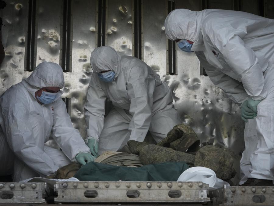 I militari ucraini identificano i corpi di soldati russi in un vagone frigorifero ferroviario a Kiev. (AP Photo/Efrem Lukatsky)