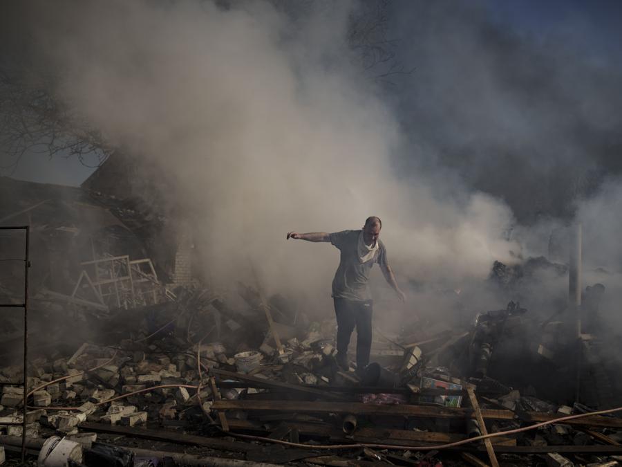 Un vicino cammina sulle macerie di una casa in fiamme, distrutta dopo un attacco russo a Kharkiv. (AP Photo/Felipe Dana)