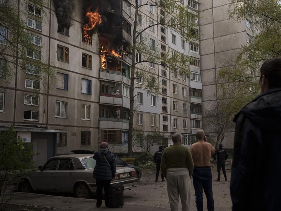 La gente guarda mentre un edificio residenziale brucia in seguito a un bombardamento russo a Kharkiv. (AP Photo/Felipe Dana)