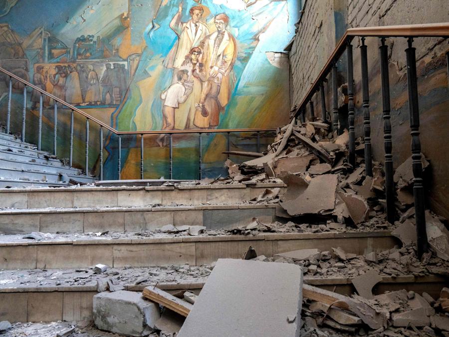 Detriti vicino a  un murales su una scala dell’edificio dell’Università Pedagogica di Kharkiv, distrutto da un missile. (Photo by SERGEY BOBOK / AFP)