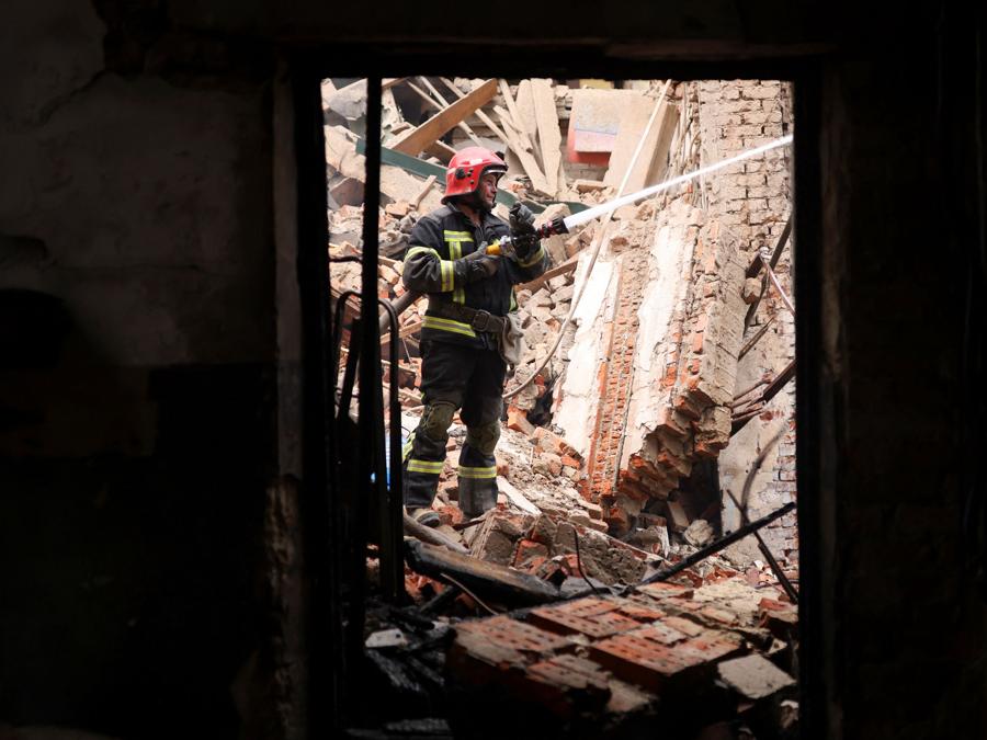 Un vigile del fuoco lavora mentre altri rimuovono i detriti per trovare corpi di persone presso la Casa Centrale della Cultura, dopo che un attacco militare ha colpito l’ edificio,  a Chuhuiv. REUTERS/Nacho Doce