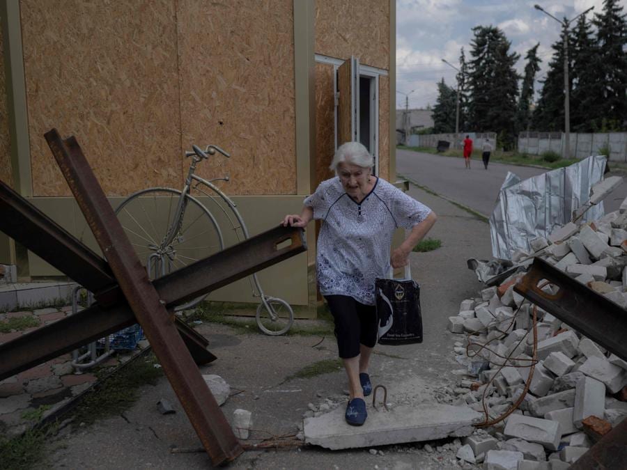 Una donna anziana si fa strada tra le macerie vicino a un mercato a Bakhmut. (Photo by Bulent KILIC / AFP)