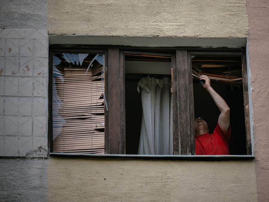 Un uomo chiude la finestra rotta della sua casa colpita da un attacco missilistico a Kharkiv. (Photo by AFP)