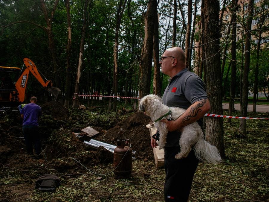 Un uomo con un cane guarda un cratere a seguito di un attacco missilistico sulla seconda città ucraina più grande, Kharkiv. (Photo by AFP)