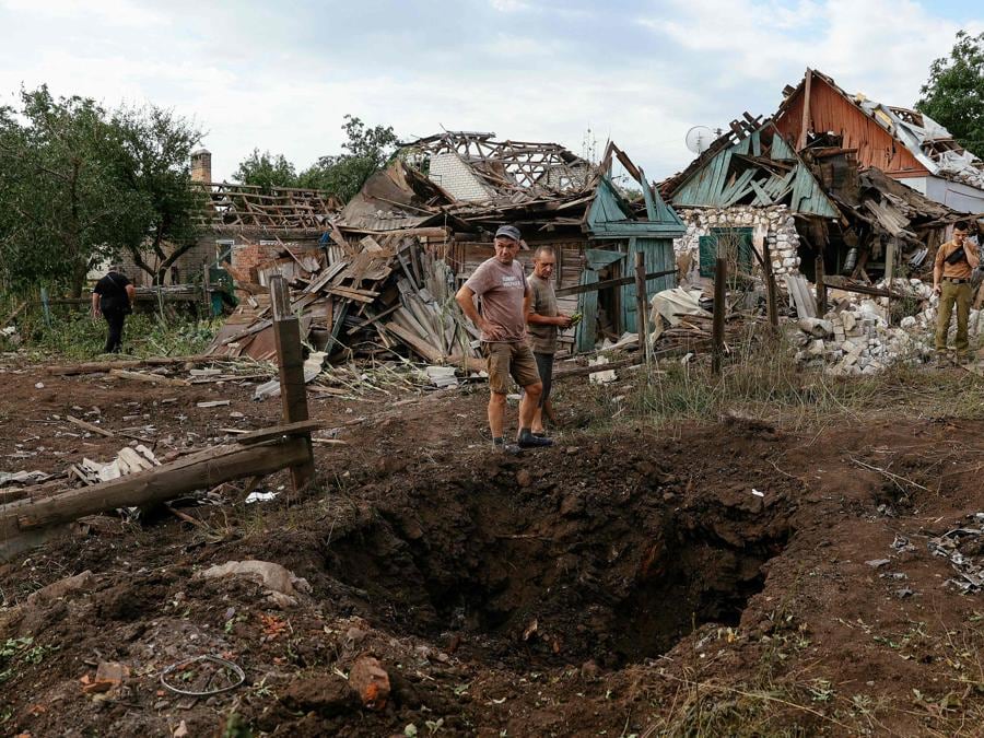 I residenti locali si trovano accanto agli edifici distrutti a seguito di un attacco missilistico nella città di Kramatorsk nella regione di Donetsk. (Photo by ANATOLII STEPANOV / AFP)