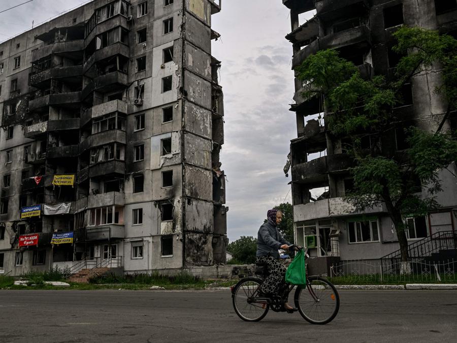 Una donna va in bicicletta davanti a un edificio residenziale distrutto nella città di Borodyanka . (Photo by Genya SAVILOV / AFP)