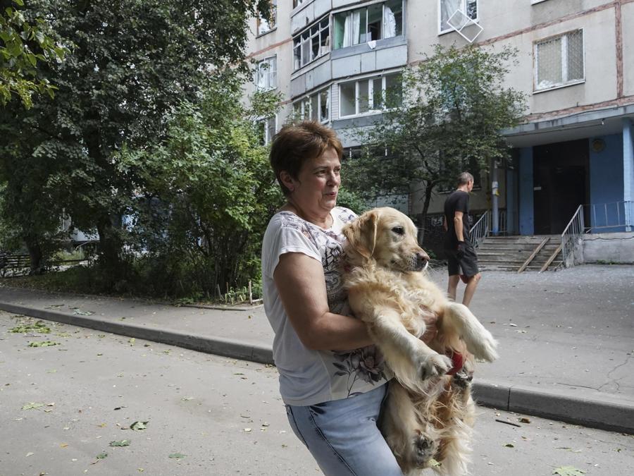 Una donna del posto porta in braccio il suo cane per salvargli le zampe da frammenti di vetri rotti dopo il bombardamento di un edificio residenziale a Kharkiv. EPA/VASILIY ZHLOBSKY