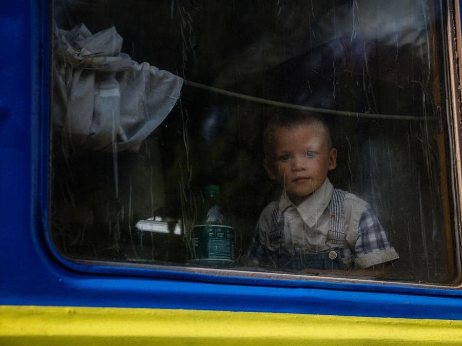 Un bambino guarda fuori dal finestrino su un treno di evacuazione dalla regione del Donbas a ovest dell’Ucraina, nella stazione ferroviaria di Udachnoye. (Photo by ANATOLII STEPANOV / AFP)