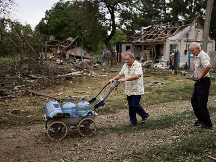 Un uomo spinge i contenitori dell’acqua accanto alle case distrutte a Kramatorsk. REUTERS/Nacho Doce 