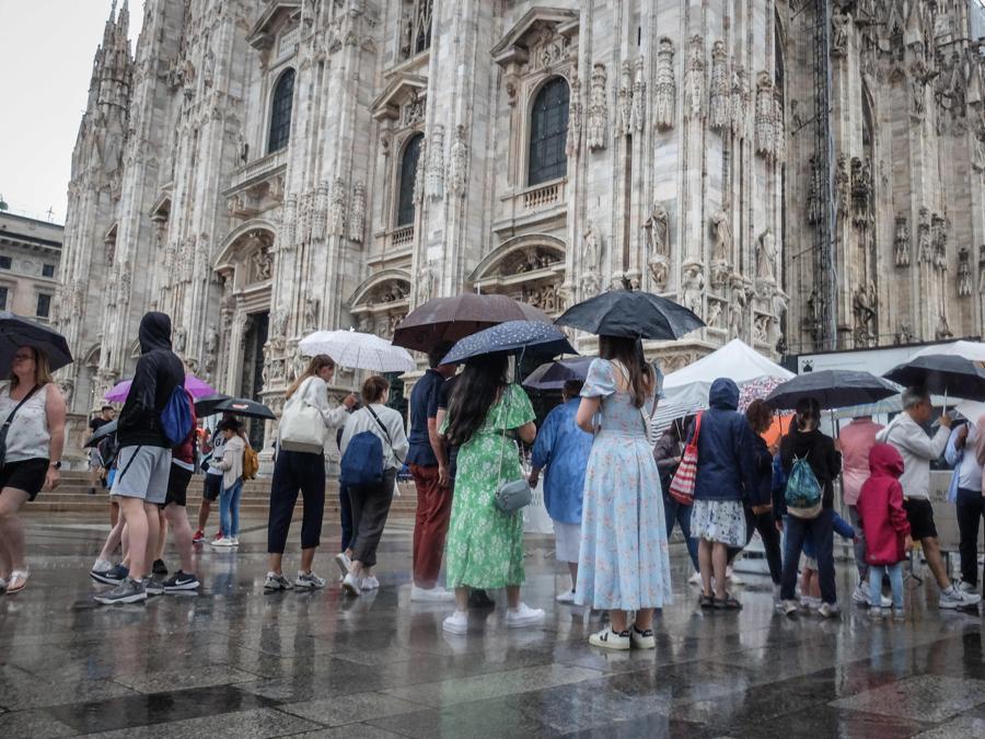 Persone si riparano con gli ombrelli dalla pioggia nel centro di Milano. ANSA/MATTEO CORNER