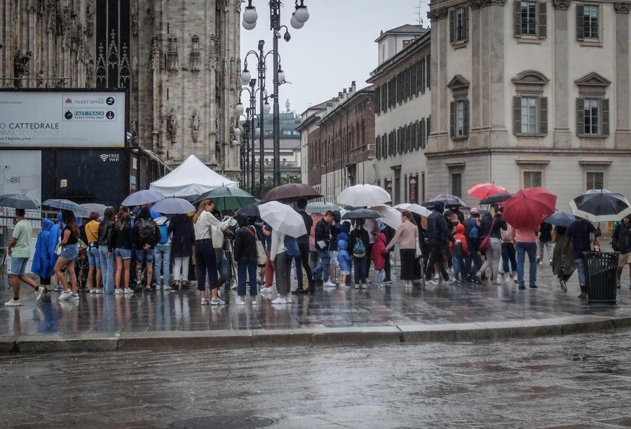 Persone si riparano con gli ombrelli dalla pioggia nel centro di Milano ANSA/MATTEO CORNER