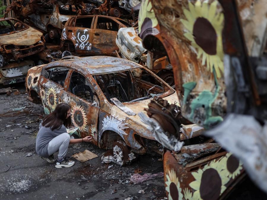 L’artista ucraina Olena Yanko dipinge un’auto distrutta durante l’attacco della Russia all’Ucraina e poi raccolta da diversi luoghi nella città di Irpin nella regione di Kiev, Ucraina. (REUTERS/Gleb Garanich)