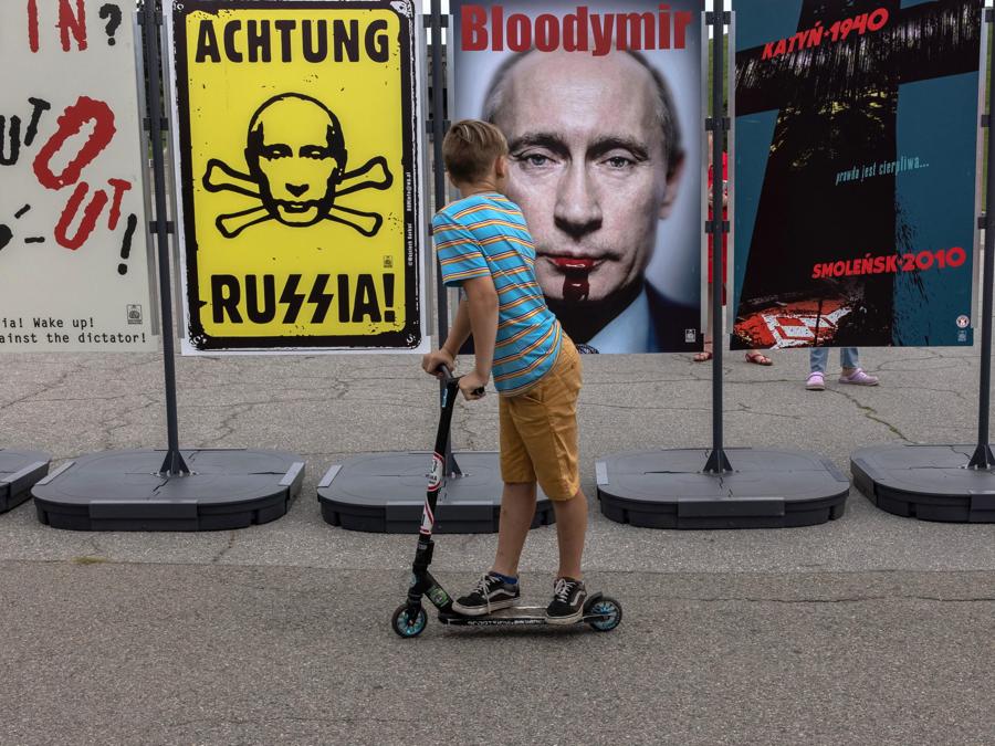 Un ragazzo guarda un poster con le sembianze del presidente russo Putin. (Epa/Roman Pilipey)