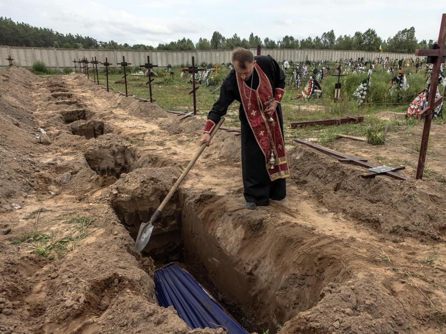 Un sacerdote ortodosso benedice i resti di persone non identificate che sono state uccise nel distretto di Bucha. (Epa/Roman Pilipey)