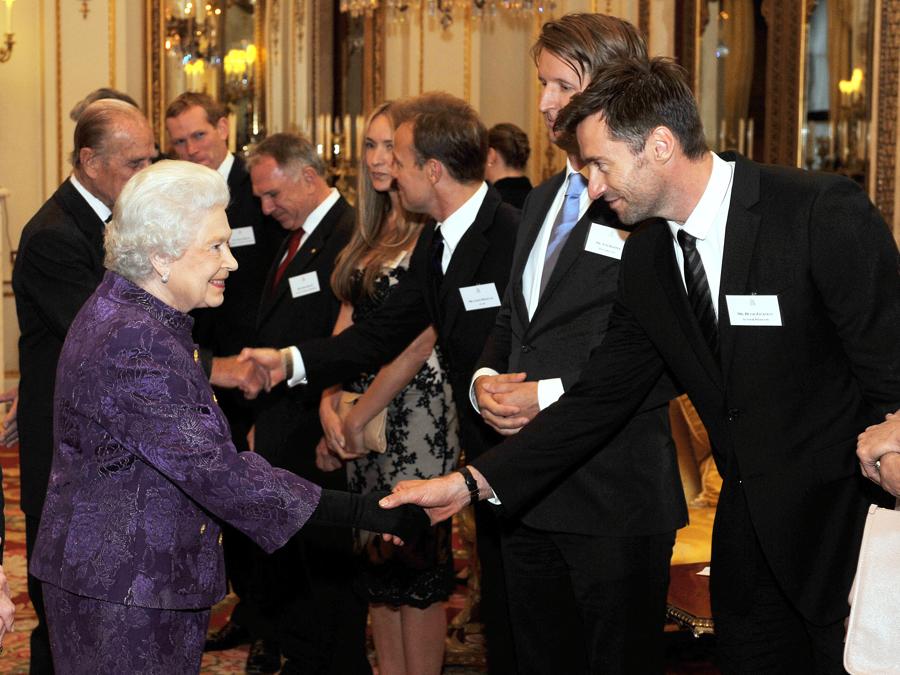 L’attore australiano Hugh Jackman (R) stringe la mano alla regina Elisabetta II, nel salotto bianco di Buckingham Palace a Londra durante un ricevimento reale per i membri della comunità australiana che vivono nel Regno Unito il 13 ottobre 2011. AFP PHOTO / POOL / John Stillwell (Photo by JOHN STILLWELL / POOL / AFP)