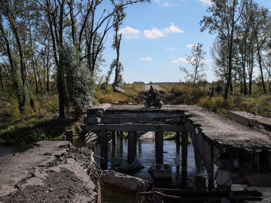 Un residente locale attraversa un ponte danneggiato vicino al villagio di Savyntsi, recentemente liberato dai militari ucraini, nella regione di  Kharkiv. (REUTERS/Gleb Garanich)