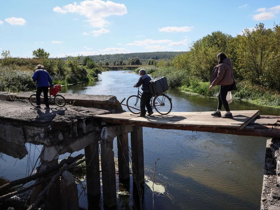 I residenti locali attraversano un ponte danneggiato mentre tornano al loro villaggio di Zalyman, nella regione di Kharkiv. (REUTERS/Gleb Garanich)