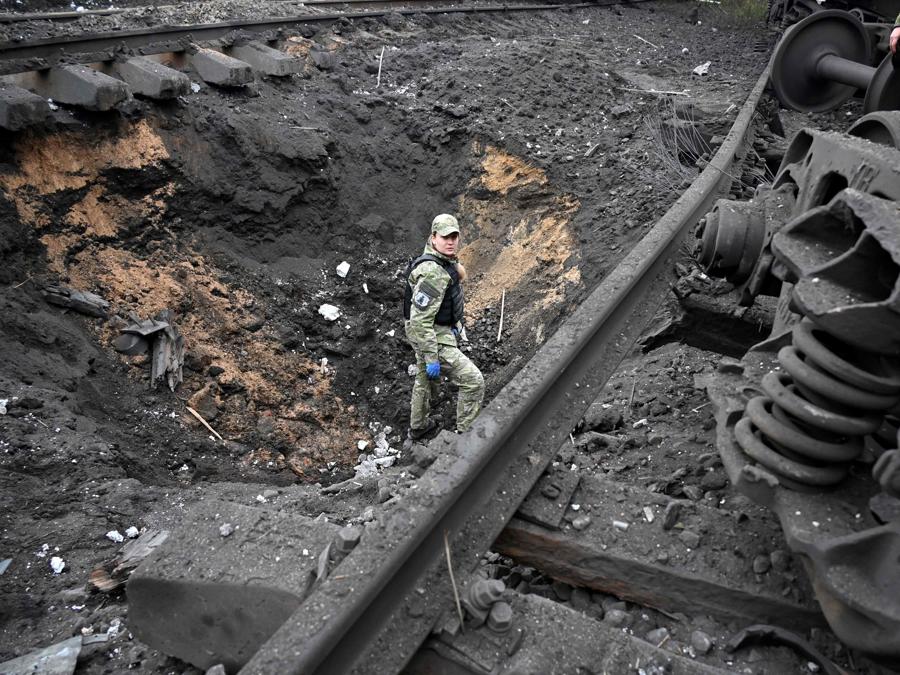Un esperto forense di esplosivi esamina il cratere dell’esplosione di un missile in una stazione ferroviaria merci a Kharkiv. (Photo by Sergey Bobok / AFP)