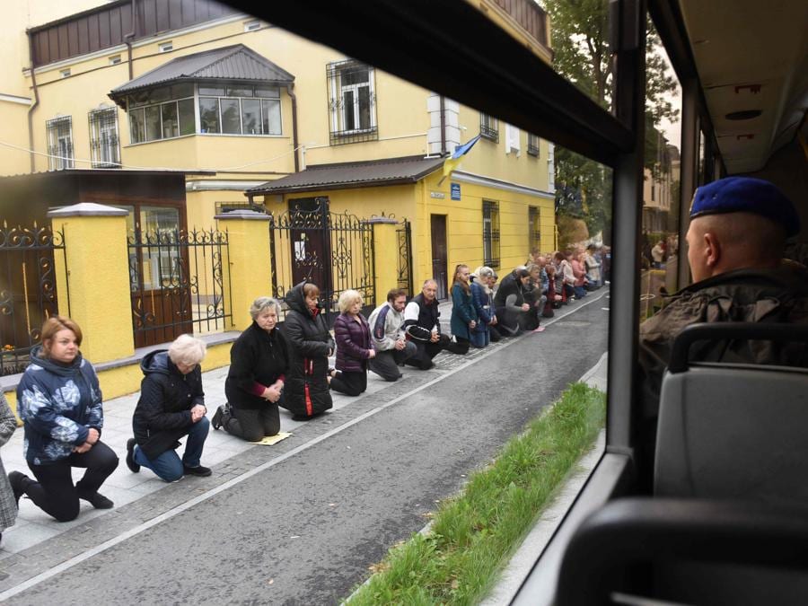 Le persone inginocchiate rendono omaggio al militare ucraino Volodymyr Haysler mentre la sua bara viene trasportata in autobus al cimitero di Lychakiv nella città di Leopoli nell’Ucraina occidentale . (Photo by Yuriy Dyachyshyn / AFP)