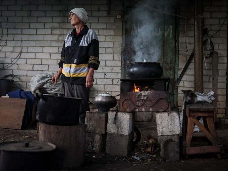 Una donna prepara da mangiare vicino alla sua casa nel villaggio di Kamyanka, recentemente liberato dalle forze armate ucraine, nella regione di Kharkiv. (REUTERS/Gleb Garanich)
