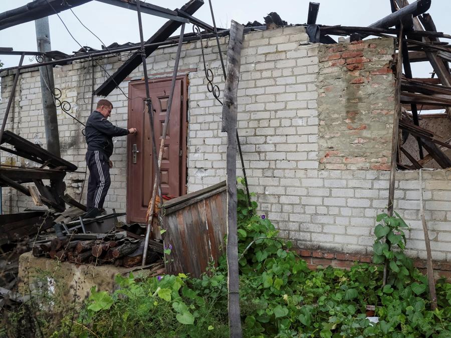 Un uomo cerca di aprire la sua casa distrutta, nel villaggio di Dolyna. (REUTERS/Gleb Garanich)