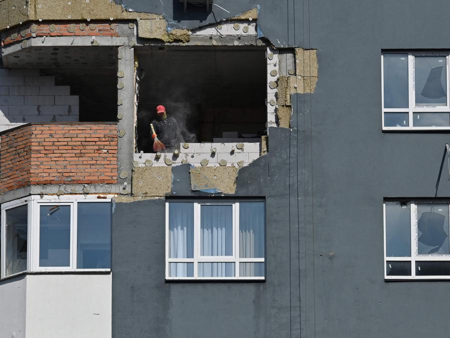 Un uomo spazza la polvere da un appartamento danneggiato durante i lavori di riparazione di un condominio parzialmente distrutto dai bombardamenti a Irpin, nella regione di Kiev. (Photo by Sergei Supinsky / AFP)