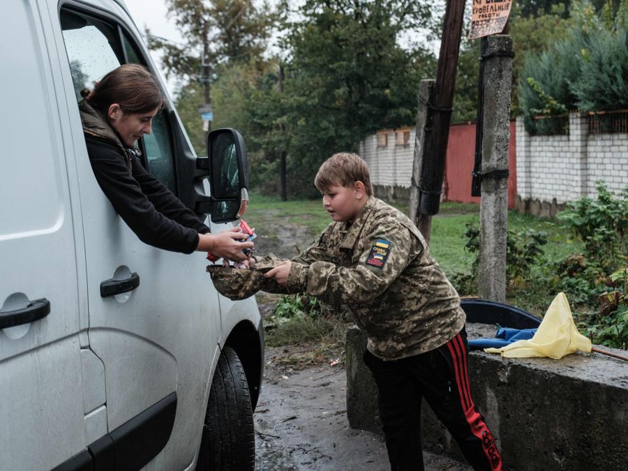Un ragazzino di  13 anni, riceve dolci da un’autista di passaggio a Chuhuiv, nella regione di Kharkiv. (Photo by Yasuyoshi Chiba / AFP)