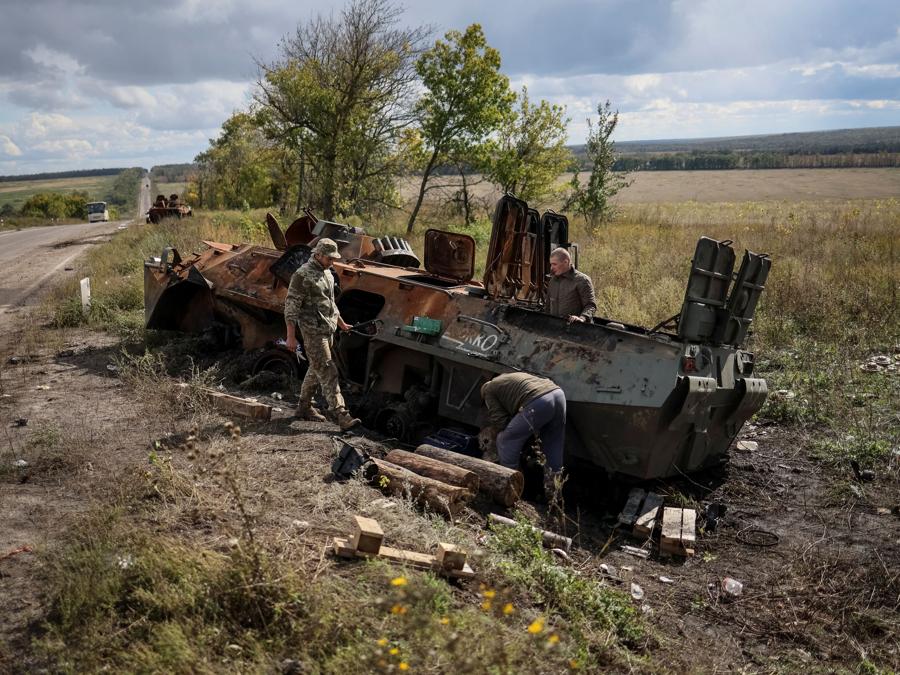 Militari ucraini esaminano una  corazzata russa  distrutta,  vicino alla città di Izium, recentemente liberata dalle forze armate ucraine, nella regione di Kharkiv. (REUTERS/Gleb Garanich)