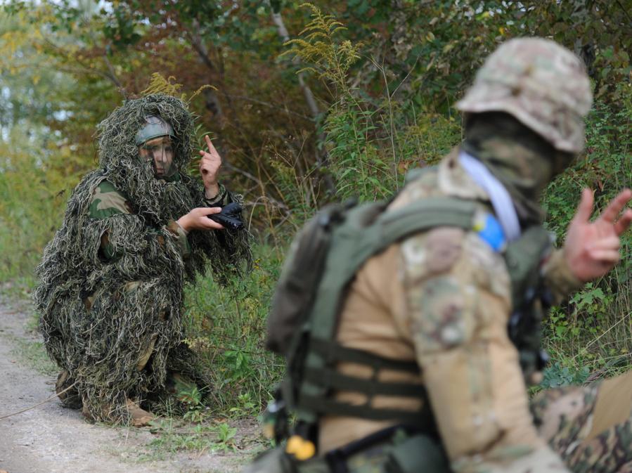 Un istruttore militare vestito con una mimetica  e con in mano una pistola (a sinistra) prende parte a un addestramento militare per civili organizzato dall’organizzazione politica ucraina Right Sector, nella regione di Lviv, Ucraina occidentale. (EPA/Mykola Tys)