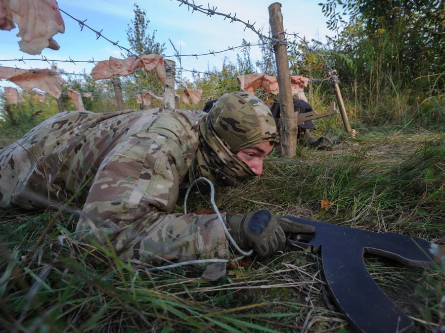 Un civile, con in mano una replica in legno di un fucile, striscia sotto il filo spinato durante l’addestramento militare organizzato dall’organizzazione politica ucraina Right Sector, nella regione di Leopoli, nell’Ucraina occidentale. (EPA/Mykola Tys)