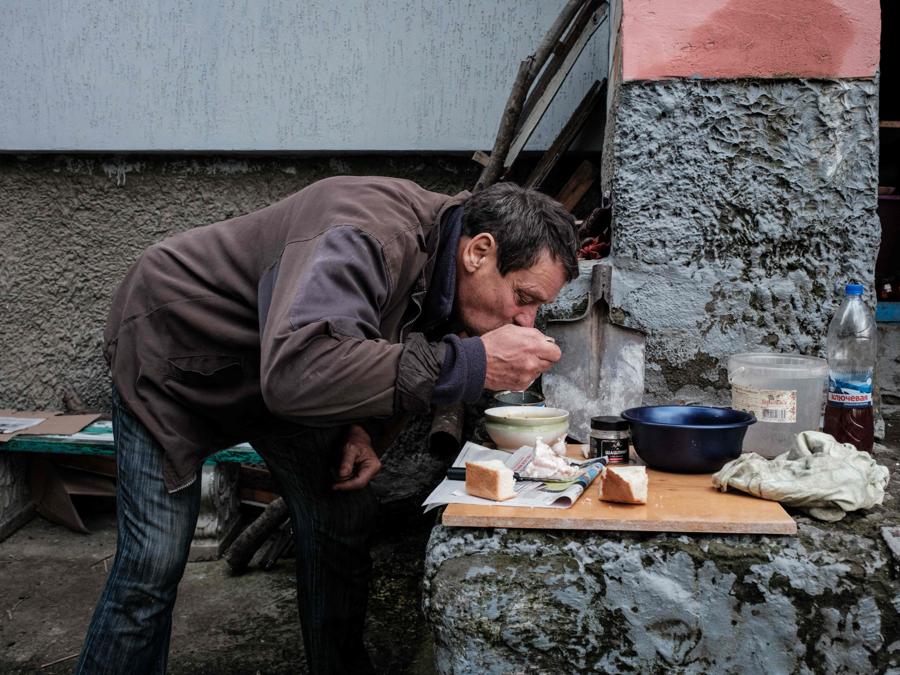 Un uomo pranza e cucina fuori all’ingresso del suo appartamento che non ha elettricità, gas o acqua, nella città in prima linea di Kupiansk, nella regione di Kharkiv. (Photo by Yasuyoshi Chiba / AFP)