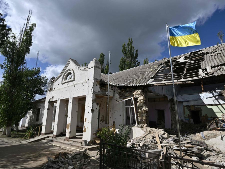 La bandiera ucraina sventola davanti a un edificio dell’amministrazione locale distrutto in un villaggio della regione di Mykolaiv. (Photo by Genya Savilov / AFP)