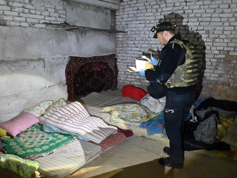 Un agente di polizia ispeziona il seminterrato di un asilo che è stato utilizzato dalle truppe come base nel villaggio di Lyptsi, nella regione di Kharkiv. (Photo by Sergey Bobok / AFP)