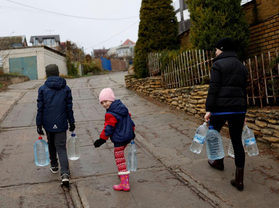 La gente si fa strada con bottiglie piene d’acqua vicino al fiume Dnipro dopo la ritirata militare della Russia da Kherson. REUTERS/Murad Sezer 