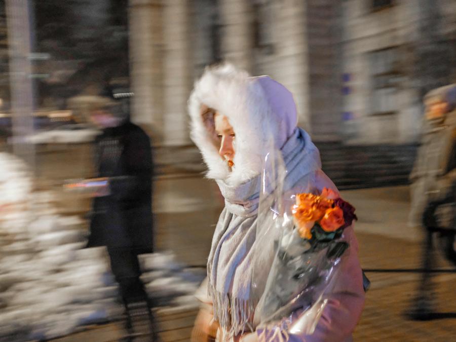 Una donna a piedi tiene delle rose per strada a Kiev. (Photo by BULENT KILIC / AFP)
