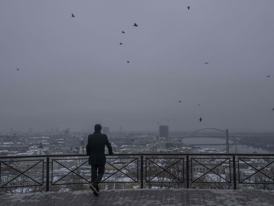 Un uomo osserva da una collina la città di Kiev. (Photo by BULENT KILIC / AFP)