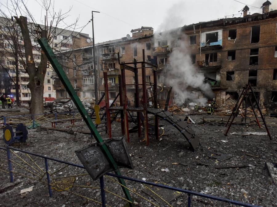 Un parco giochi per bambini distrutto mentre i vigili del fuoco (retro) lavorano presso il sito di un condominio colpito dai bombardamenti a Vyshhorod, vicino a Kiev. EPA/OLEG PETRASYUK