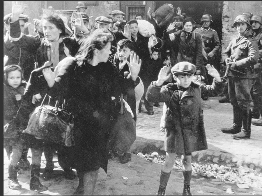 German soldiers pointing their weapons at women and children during the suppression of the Warsaw Ghetto Uprising (Yad Vashem)