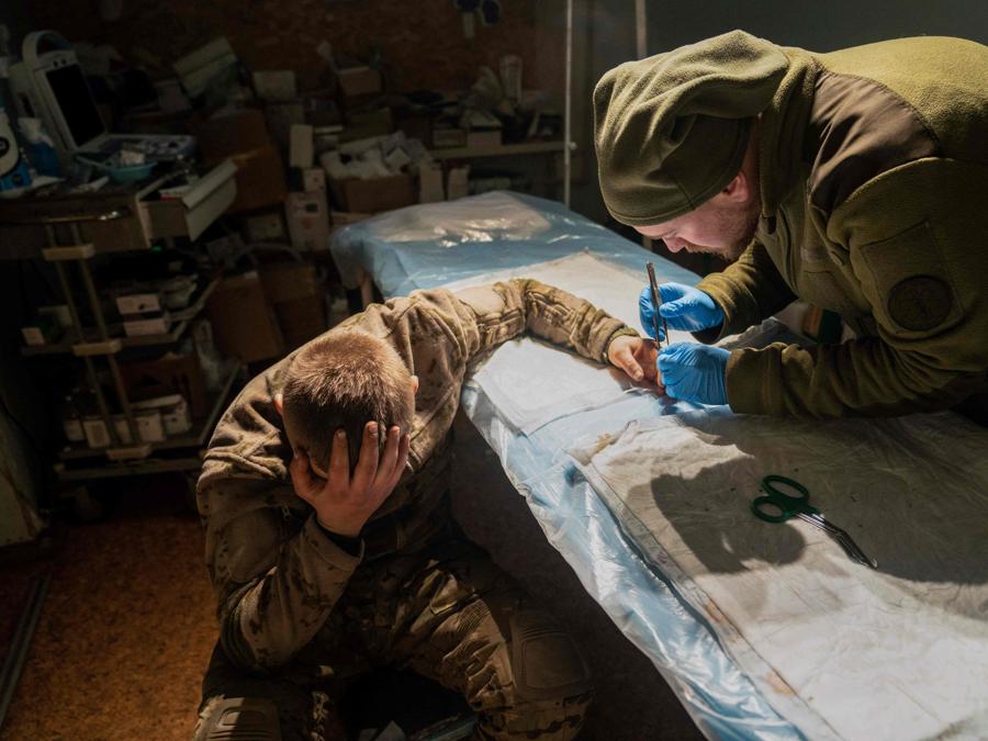 Un medico militare opera un soldato ucraino leggermente ferito in un ospedale di stabilizzazione vicino alla linea del fronte nella regione di Donetsk. (Photo by Ihor Tkachov / AFP)