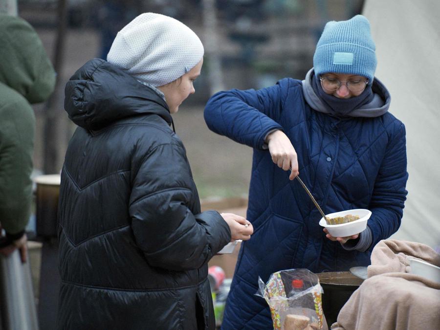 Un volontario versa del cibo in una ciotola in un punto di distribuzione di pasti caldi per i residenti locali di un edificio residenziale nella città ucraina di Dniproity (Photo by Vitalii Matokha / AFP)