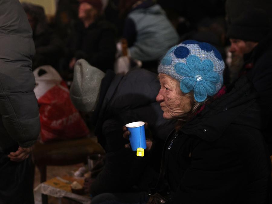 Un’anziana residente locale beve un tè mentre si riscalda in un punto di assistenza umanitaria e riscaldamento gestito da volontari, nella città ucraina di Bakhmut, nella regione di Donetsk. (Photo by Anatolii Stepanov / AFP)