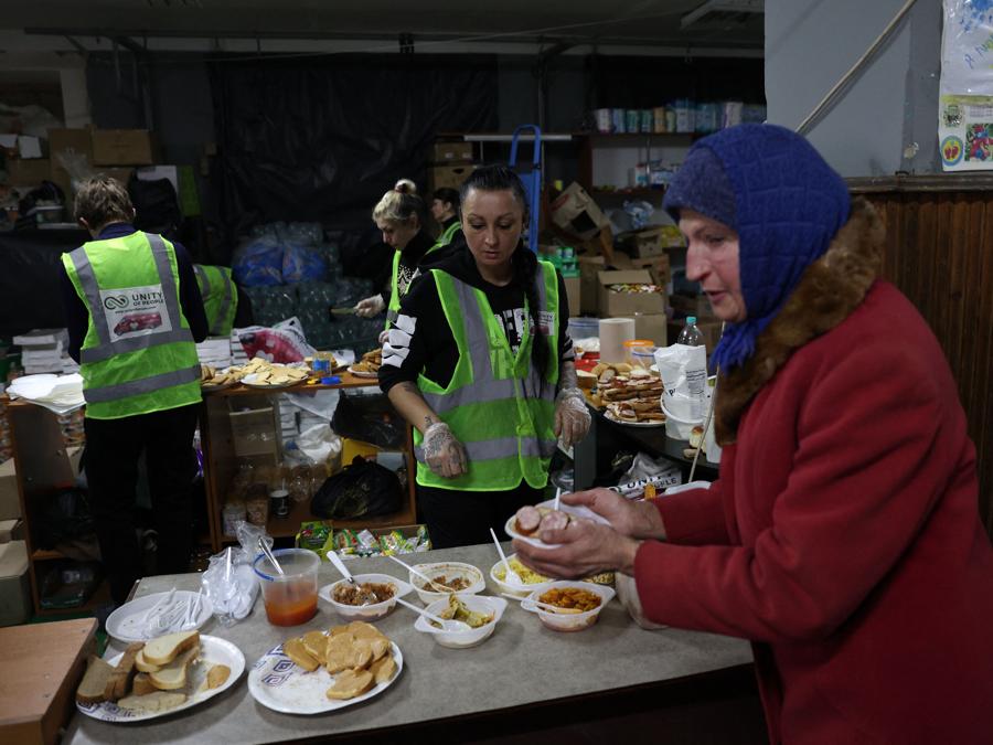 volontari distribuiscono pasti ai residenti locali in un punto di assistenza umanitaria e riscaldamento, nella città ucraina di Bakhmut, nella regione di Donetsk. (Photo by Anatolii Stepanov / AFP)
